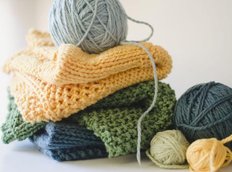 Stack of knitted blankets and balls of yarn